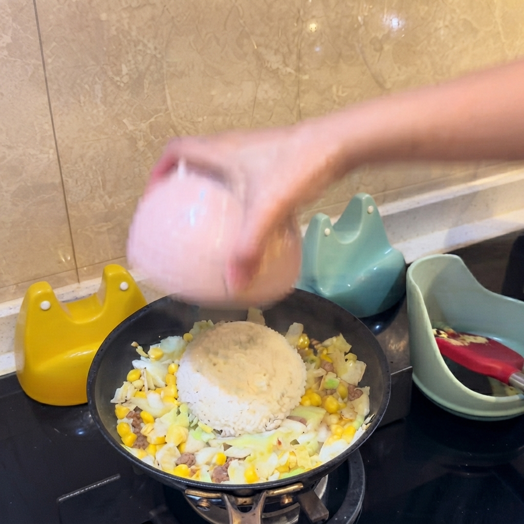Una ciotola rosa che capovolge un mucchietto di riso bianco direttamente al centro degli ingredienti nella padella.