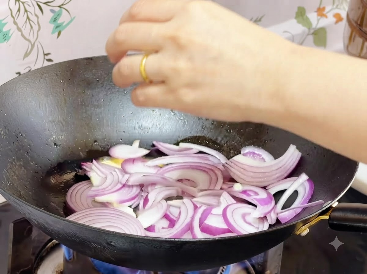 Cipolle rosse affettate saltate nel burro fuso allinterno di un wok.