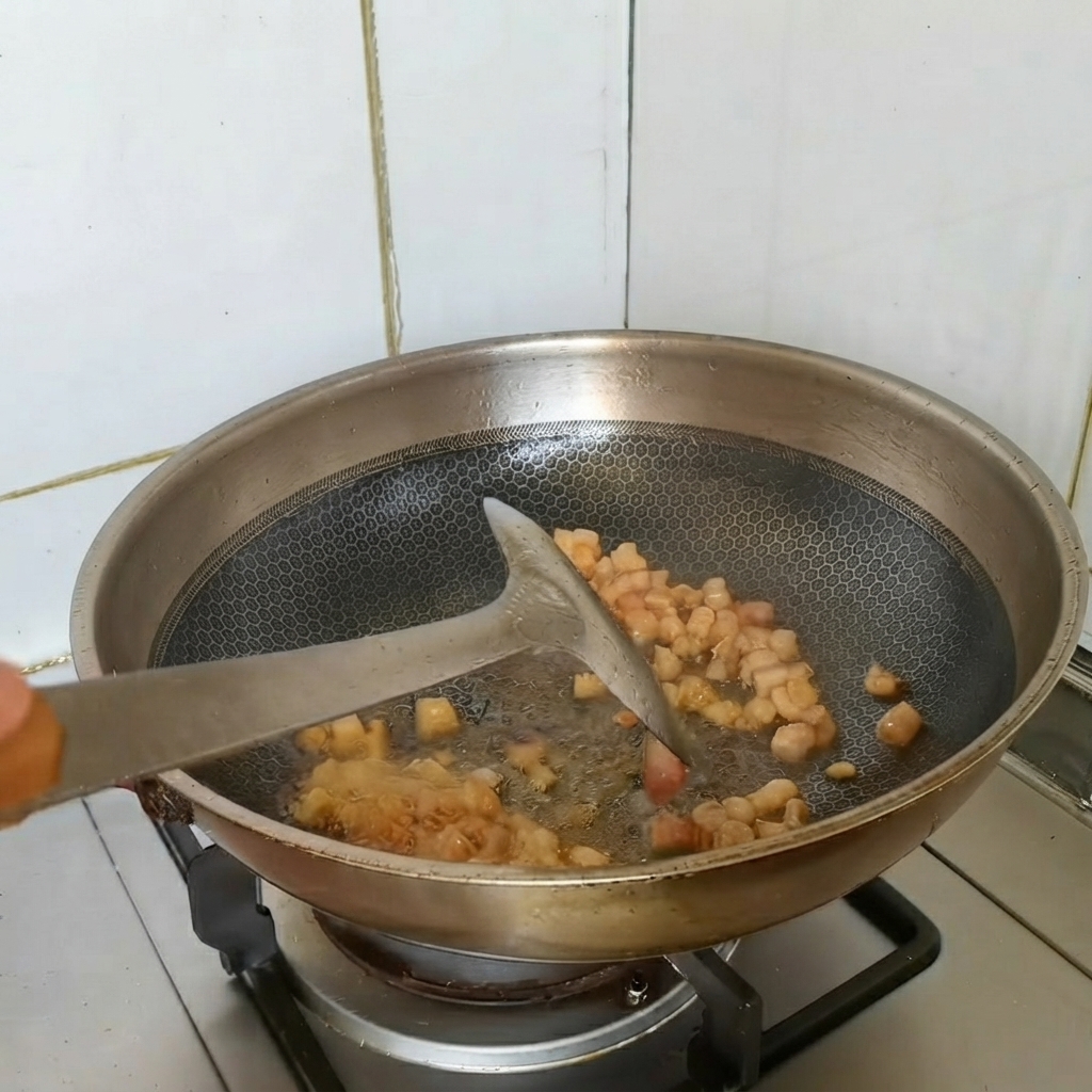 Pezzi di pancia di maiale dorati saltati in padella in un wok con gli aromi.