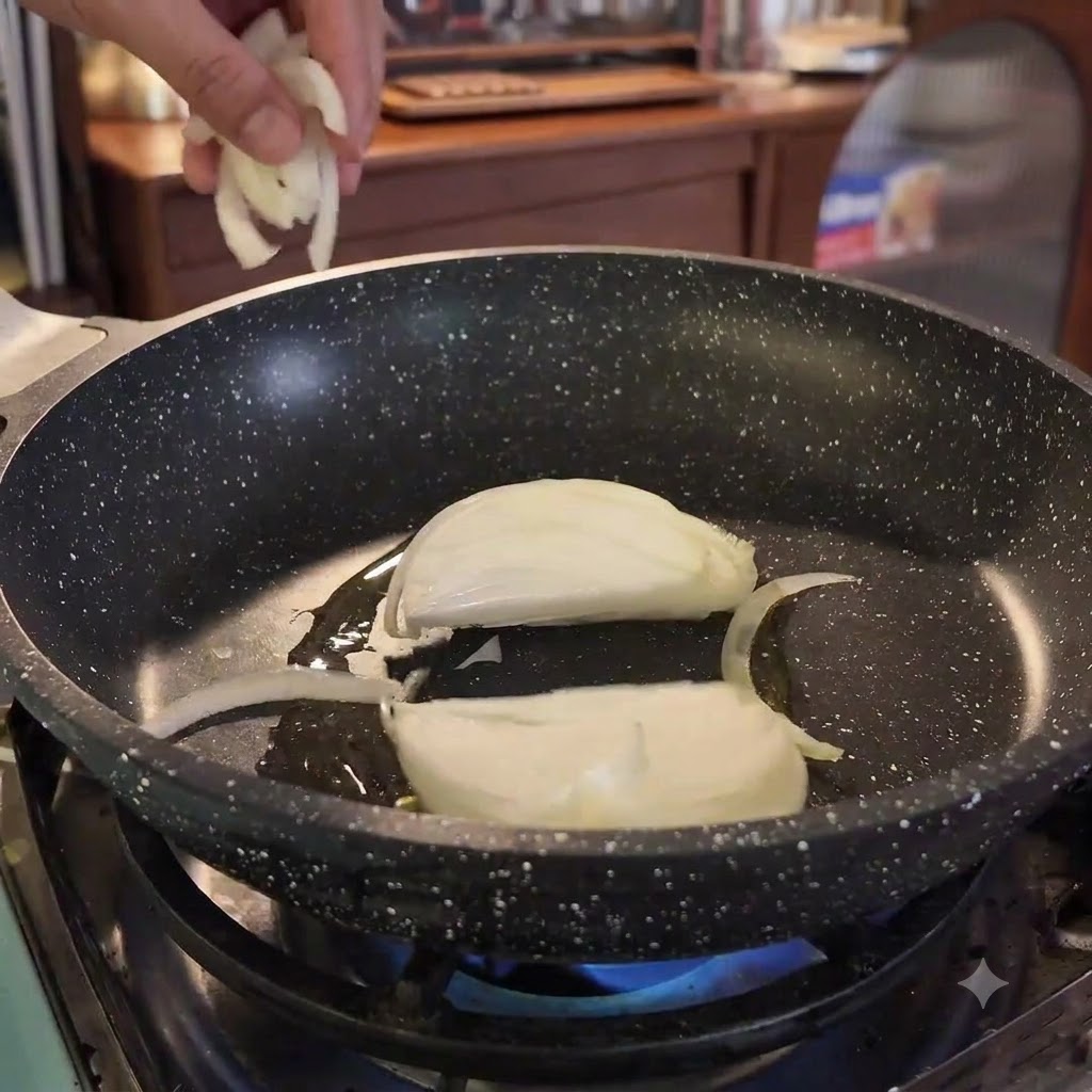 Fette di cipolla aggiunte in una padella calda con olio sopra una fiamma blu.