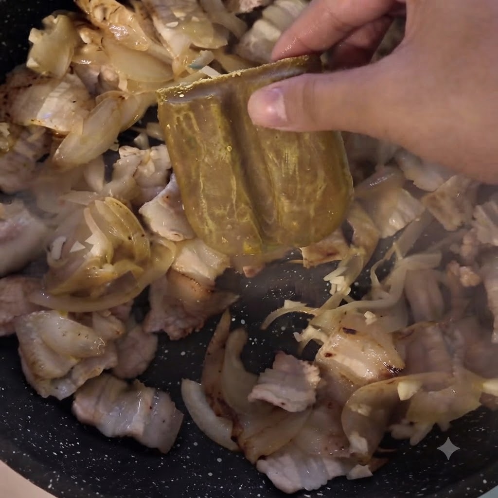 Un blocco di pasta di curry aggiunto alla padella contenente carne e cipolle.
