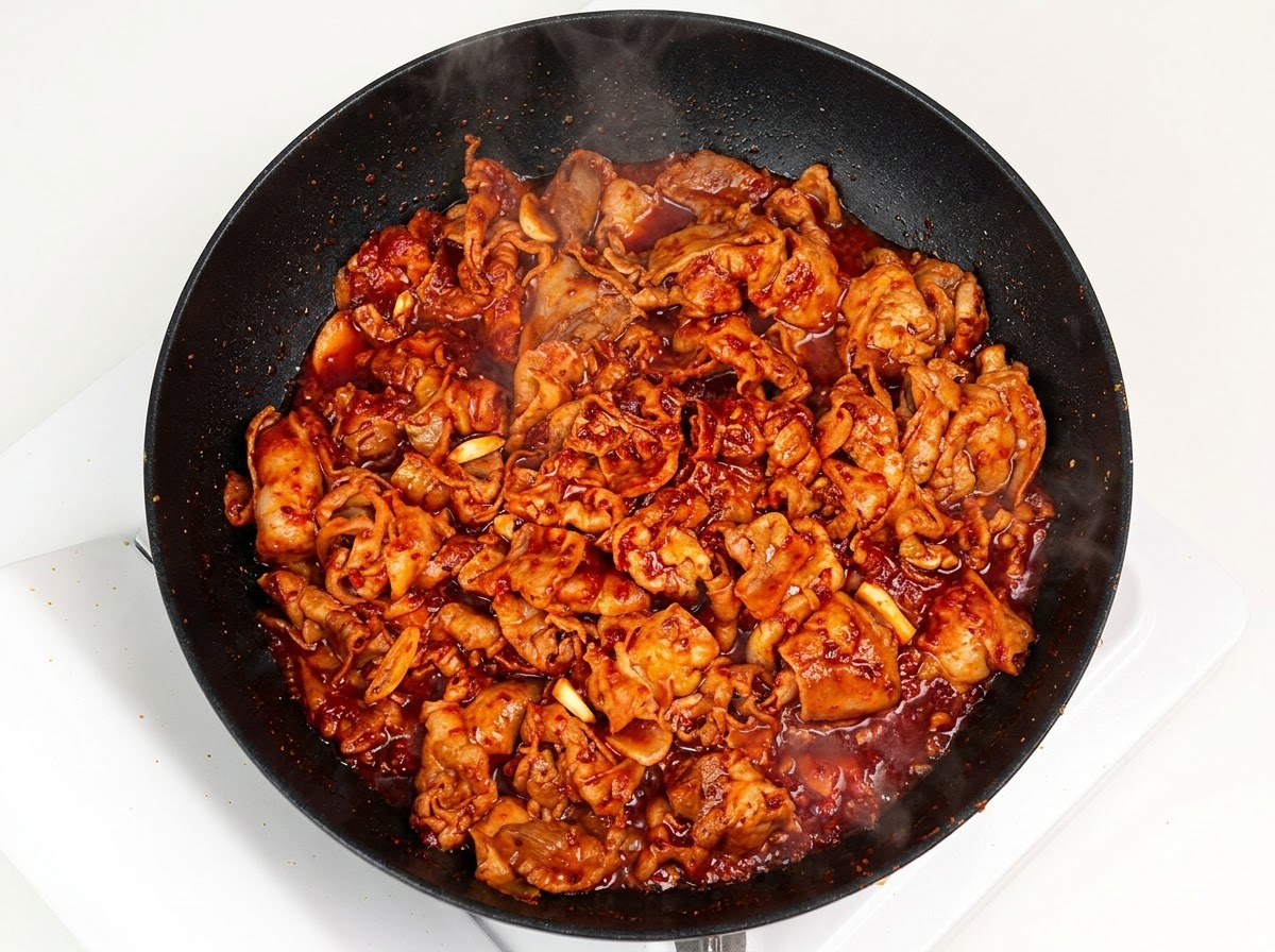 Cipolla bianca tagliata a julienne aggiunta nella padella con la carne speziata.