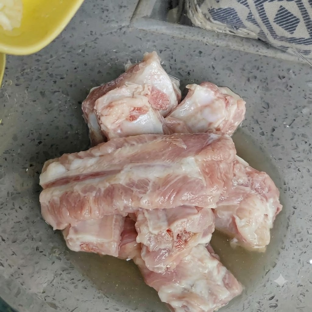 Ciotola di costine di maiale crude con aglio fresco tritato aggiunto sopra.