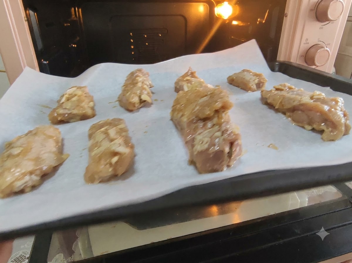 Costine di maialeimate disposte ordinatamente su carta da forno allinterno di una teglia pronte per il forno.