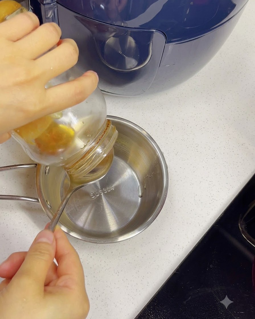 Miele versato da un barattolo in una ciotola di acciaio inossidabile con acqua usando un cucchiaio.