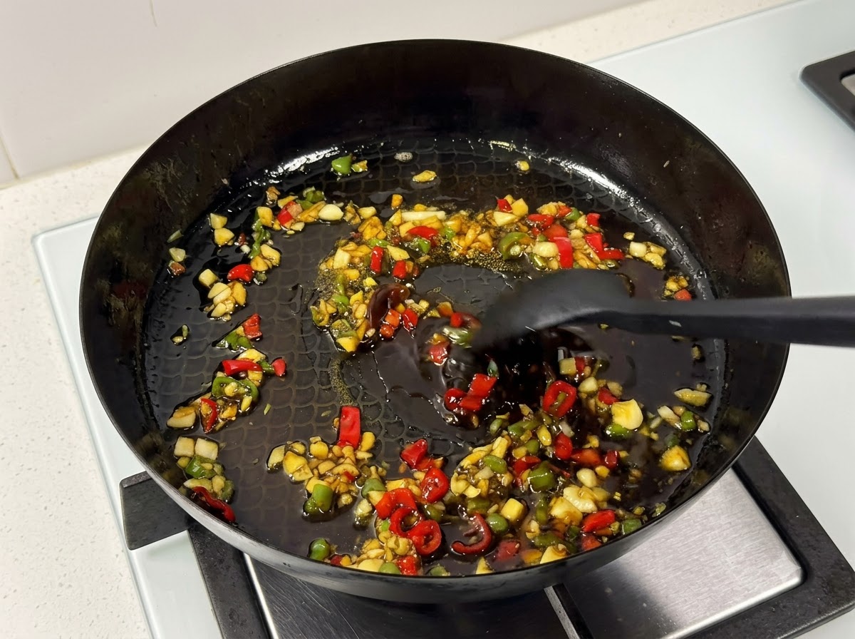 Una spatola da cucina che mescola le costine di maiale e la salsa allinterno di una padella sul fuoco.