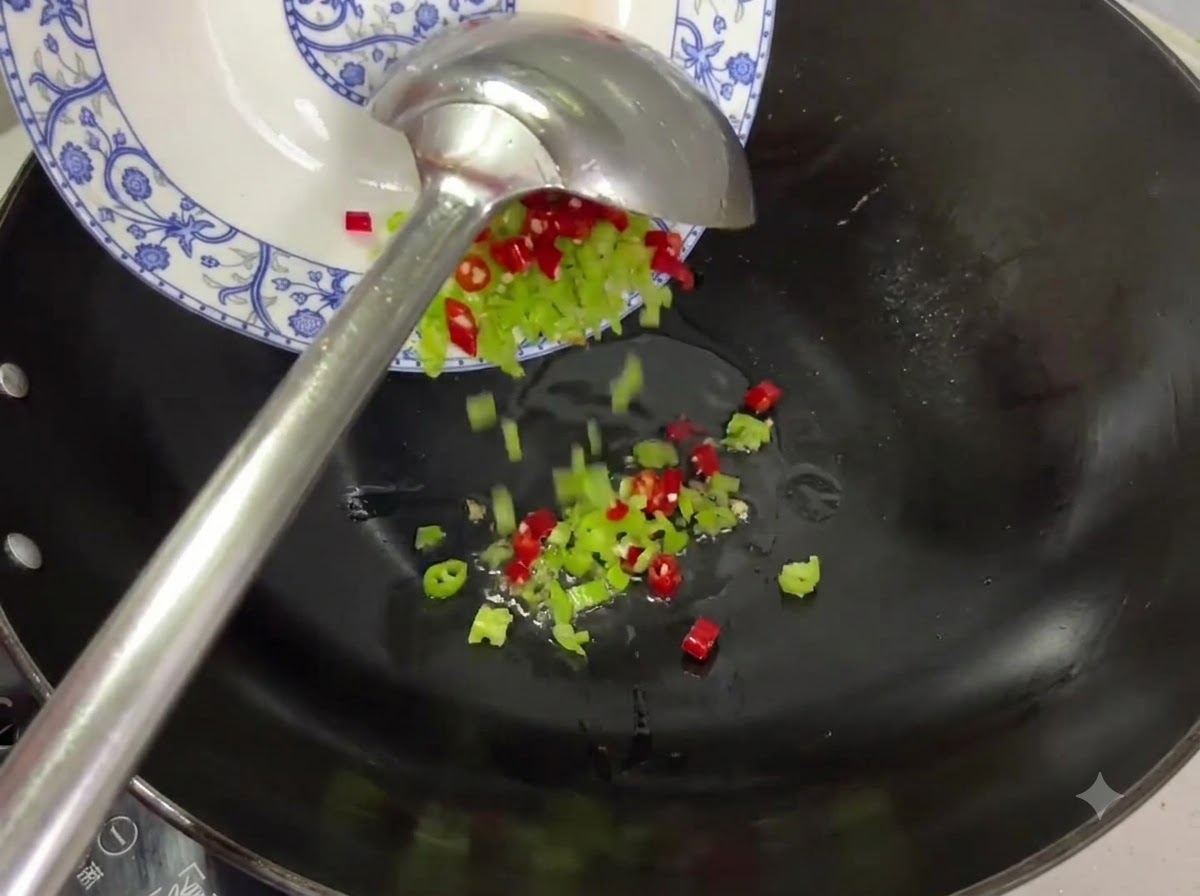 Pezzi di peperoncino rosso e verde versati da un piatto in un wok con olio.