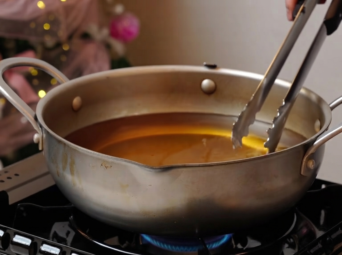 Costine di maiale che friggono delicatamente in unampia pentola dolio su un fornello.