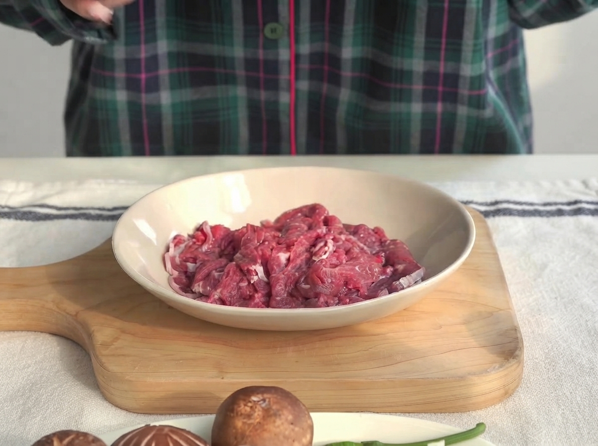 Pezzi di filetto di manzo in una ciotola bassa marinati con salsa di ostriche e amido di mais.