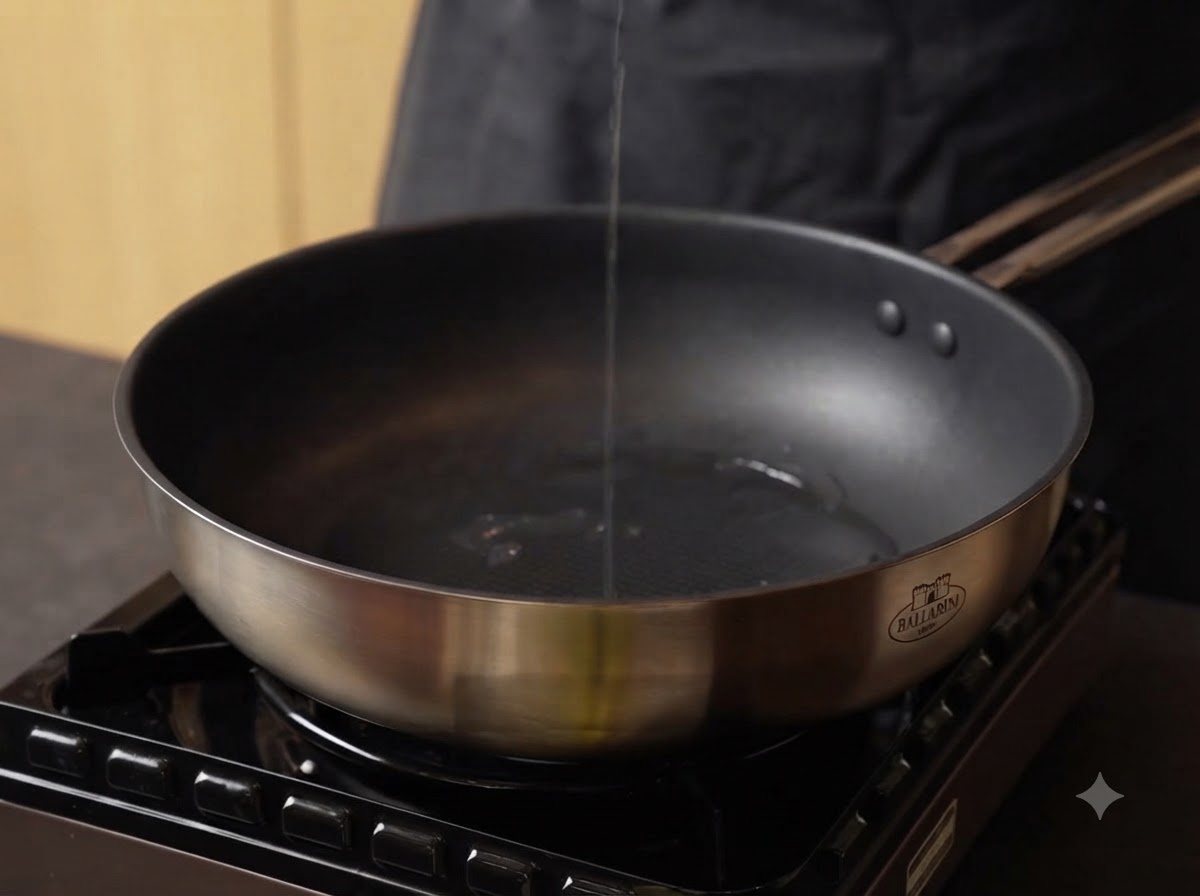 Olio versato in una padella di acciaio inossidabile calda su un fornello.