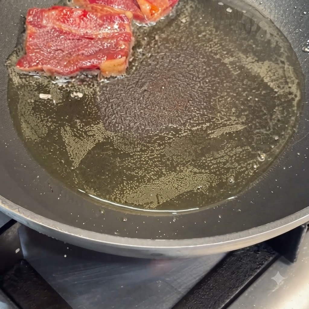 Costolette di manzo marinate che soffriggono nellolio caldo in una padella.