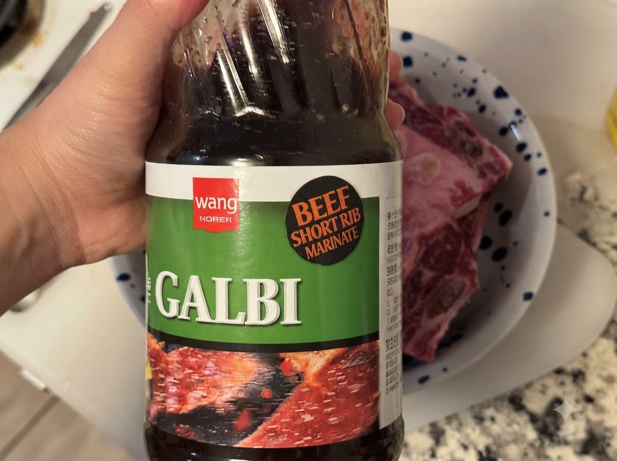 Una bottiglia di salsa coreana BBQ Galbi versata in una ciotola contenente costine di manzo crude.