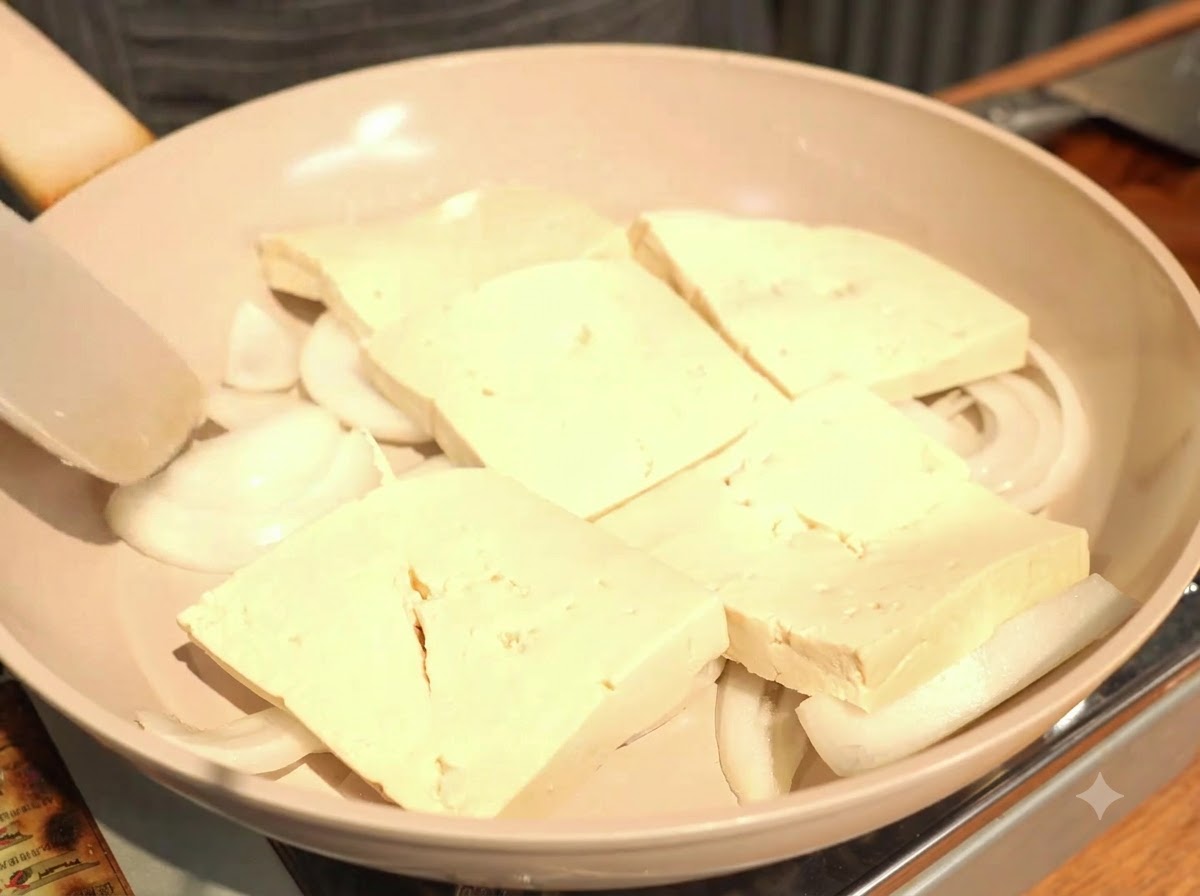 Disporre le spesse fette di tofu in un unico strato leggermente sovrapposto sopra le cipolle.