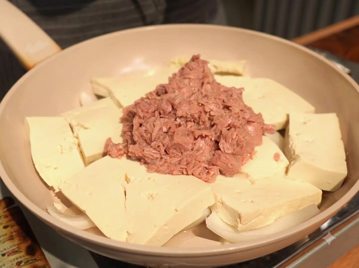 Aggiungere un cucchiaio di aglio tritato nella padella, posandolo sul tofu accanto al tonno.