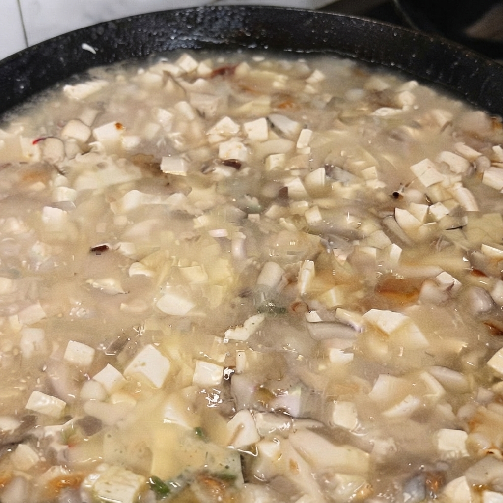 Un cucchiaio di glutammato monosodico aggiunto alla zuppa di tofu in ebollizione.