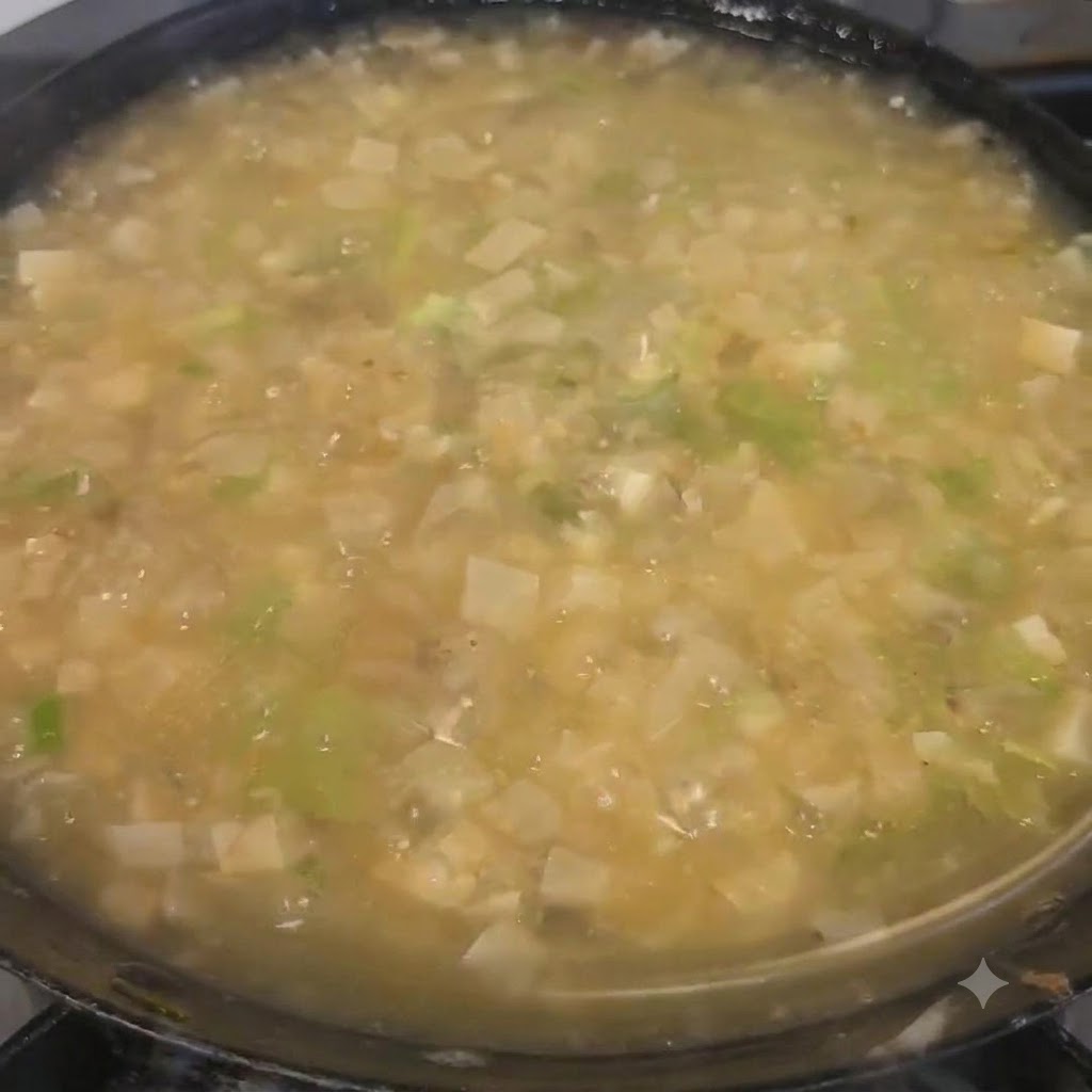 Coriandolo tritato cosparso sulla zuppa finita nella pentola.