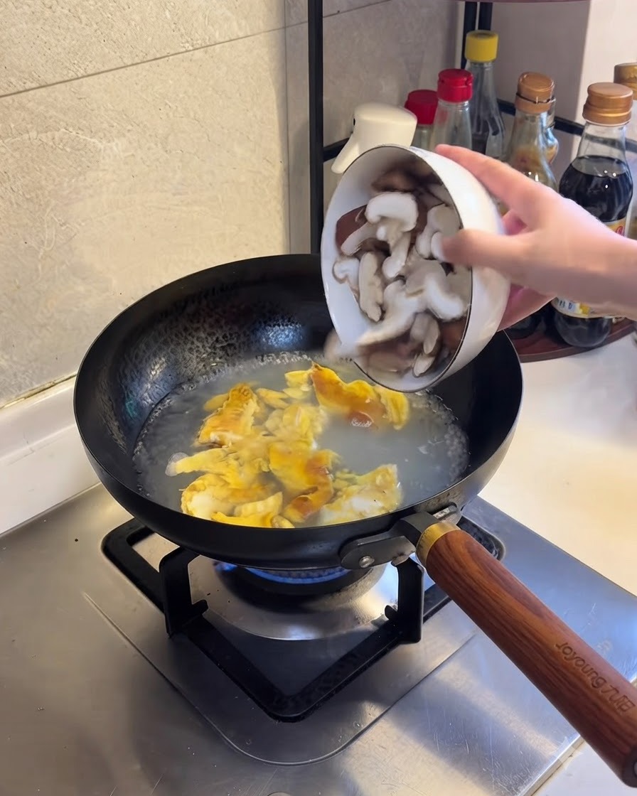 Funghi shiitake affettati aggiunti allacqua bollente e al composto di uova.