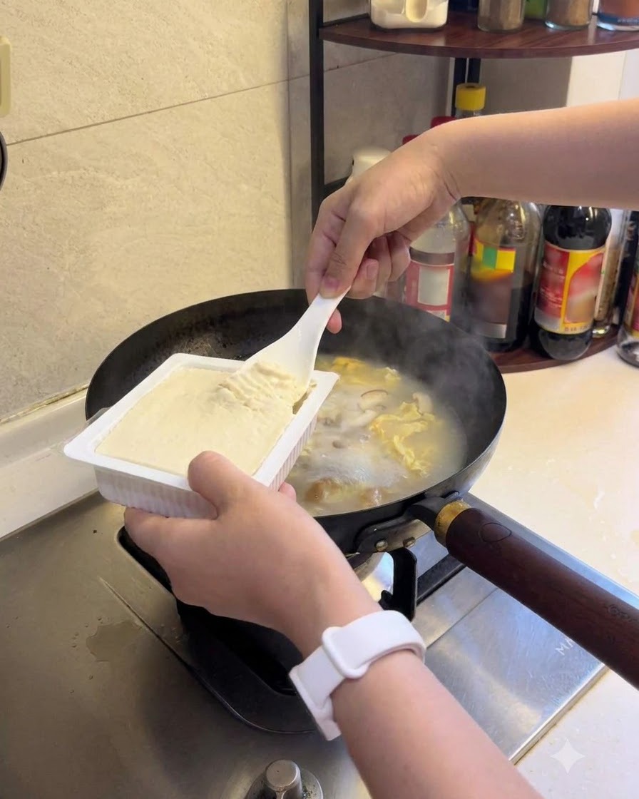 Tofu morbido aggiunto alla zuppa in ebollizione.