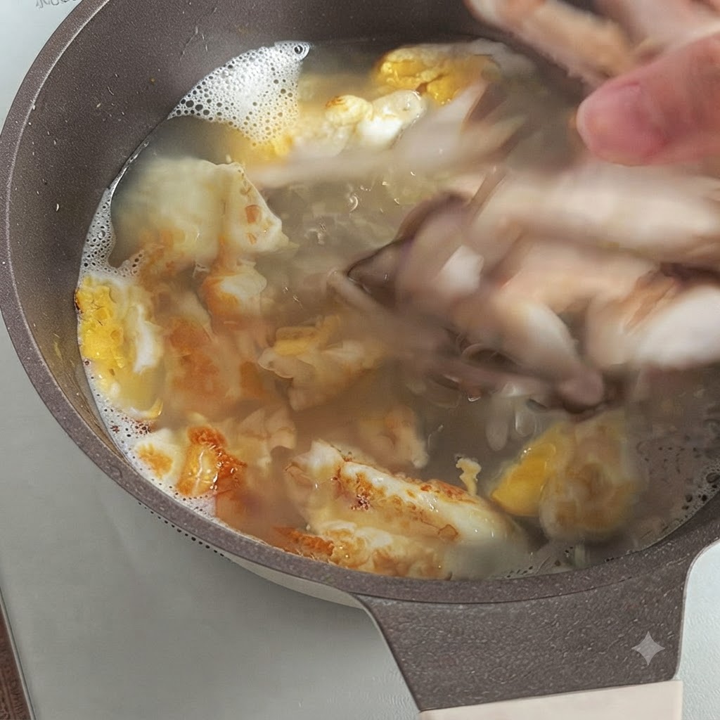 Una mano che fa cadere fette di funghi shiitake freschi in un brodo bollente con pezzi di uovo fritto.