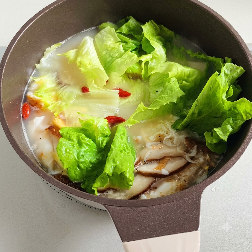 Una pentola di zuppa fumante con foglie di lattuga e bacche di goji rosse che galleggiano allinterno.