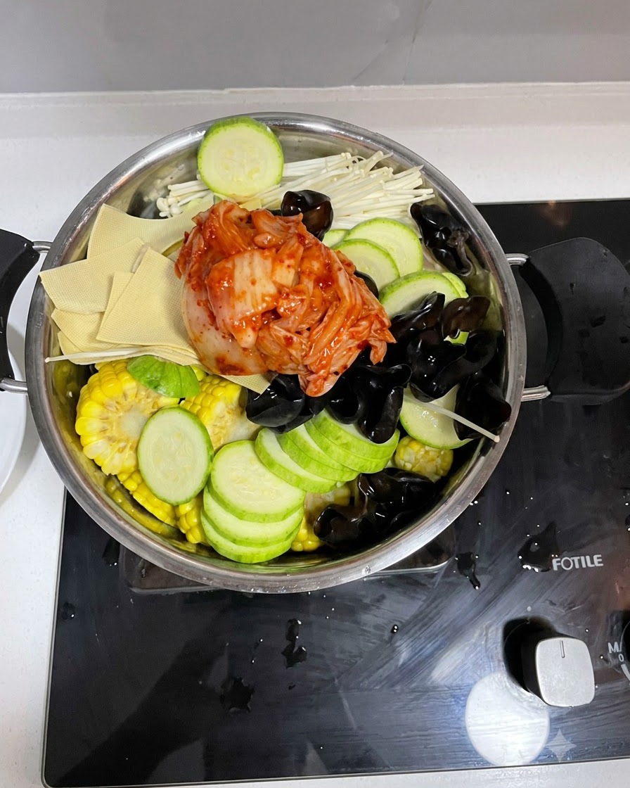 Versamento della miscela di salsa preparata sugli ingredienti nella pentola di cottura.
