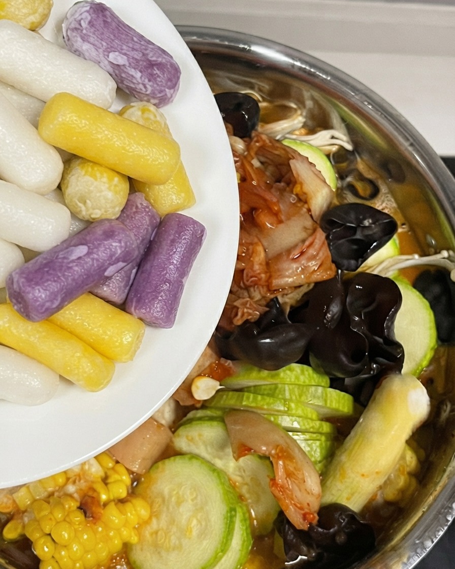 Aggiunta di colorati gnocchi di riso al formaggio nella pentola riempita con ingredienti e salsa.