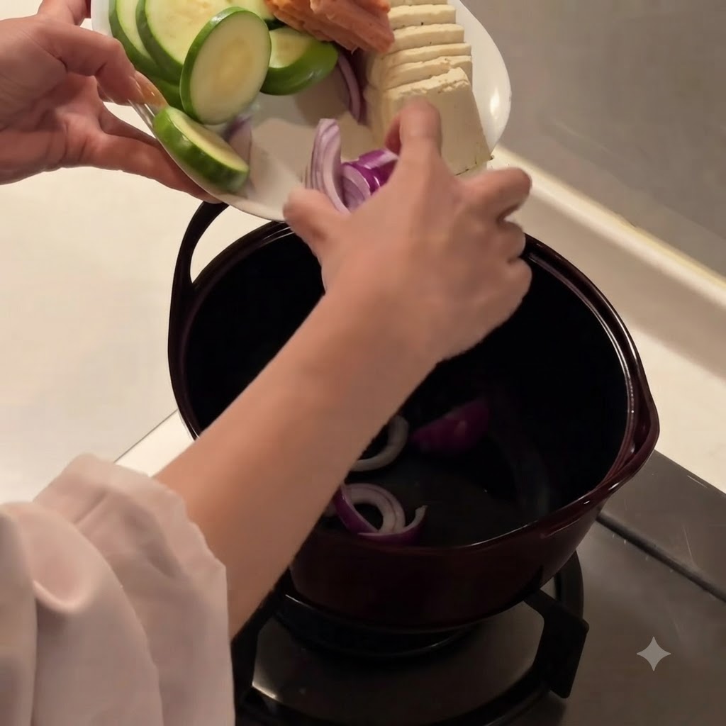 Cipolle rosse affettate posizionate sul fondo di una pentola da cucina scura.