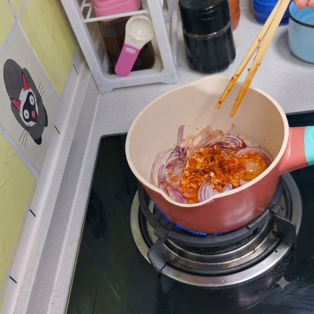 Kimchi e cipolle rosse mescolati insieme nella pentola usando delle bacchette di legno.