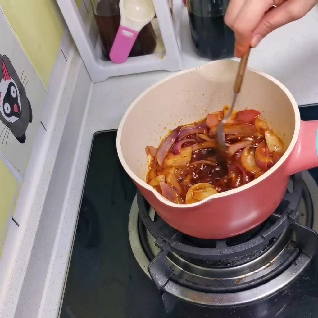 La salsa, le cipolle e il kimchi mescolati insieme nella pentola con un cucchiaio.