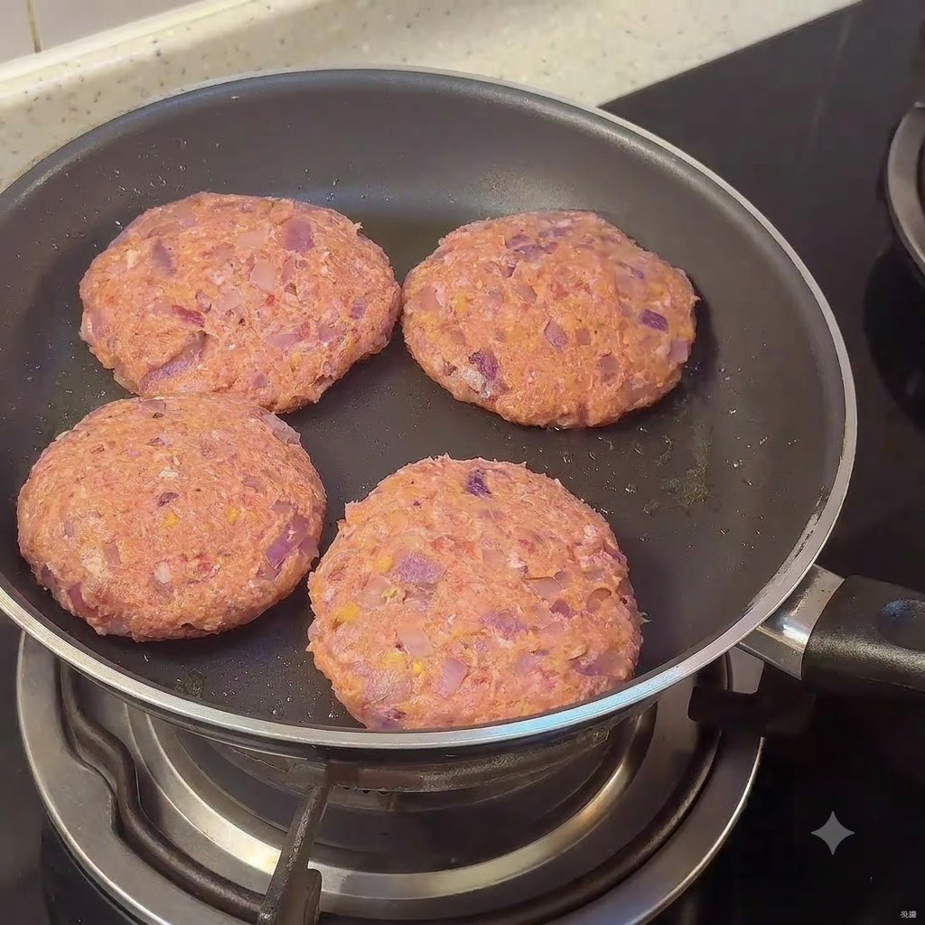 Quattro hamburger di carne crudi che sfrigolano in una padella sul piano cottura.