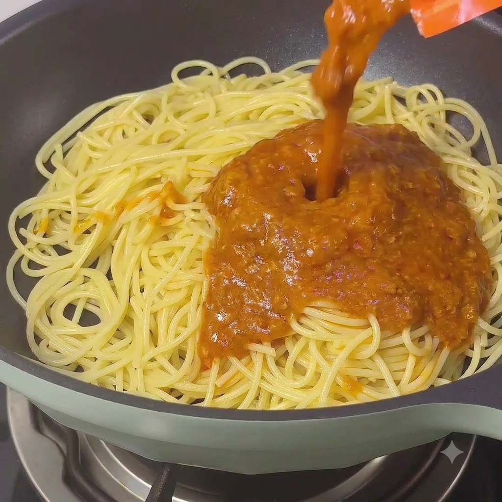 Ricca salsa bolognese classica versata sui noodles di spaghetti in una padella.