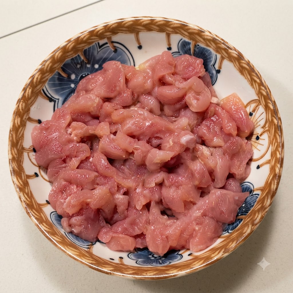 Salsa di soia scura versata sul maiale crudo a dadini allinterno di una ciotola decorativa.