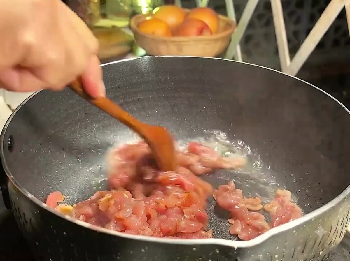 Pezzi di maiale saltati in padella con un cucchiaio di legno a fuoco medio.
