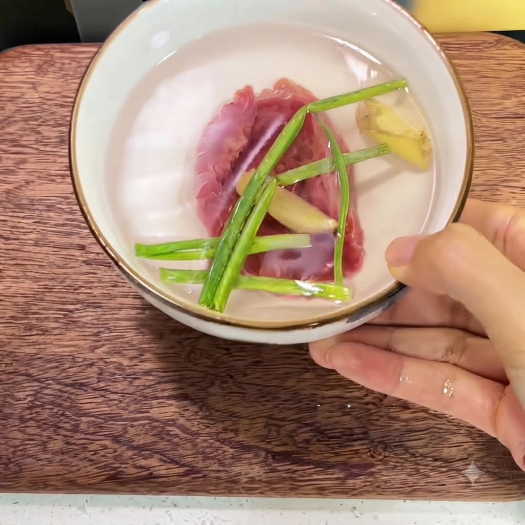 Carne di manzo fresca in una ciotola di ceramica piena dacqua, fette di zenzero e gambi di cipollotto.