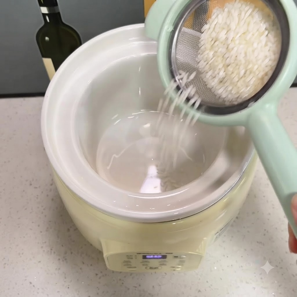 Riso lavato che cade da un piccolo colino verde nella pentola di ceramica del cuociriso.