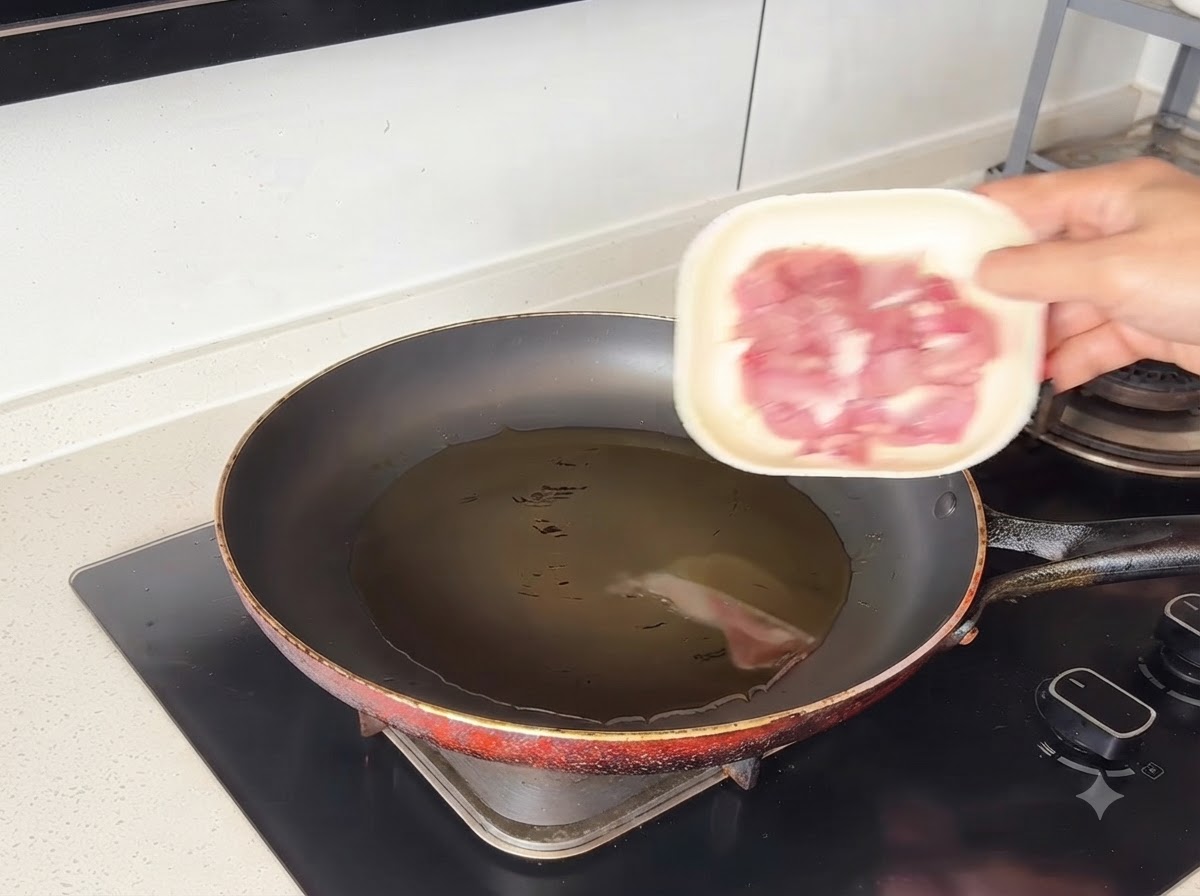 Pezzi di maiale che sfrigolano nellolio caldo allinterno di una padella.