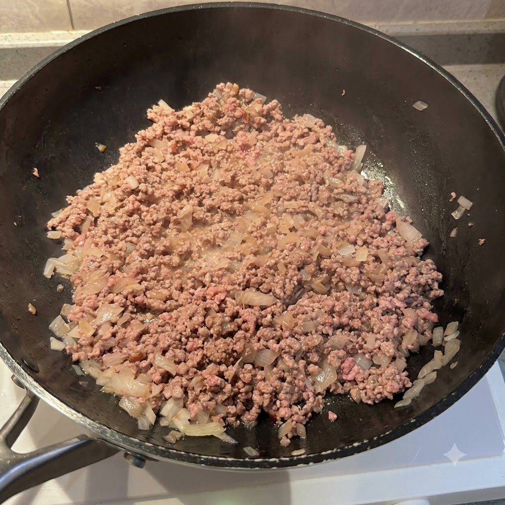 Primo piano di carne macinata e cipolle in padella condite con varie spezie in polvere.