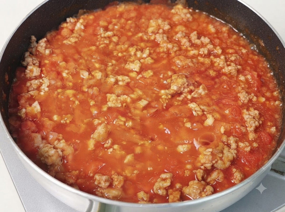Una padella di spessa salsa di carne al pomodoro che sobbolle sui fornelli.