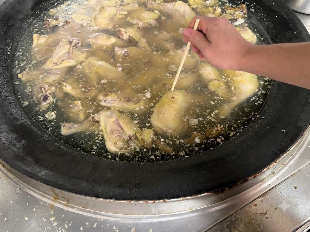 Una mano che utilizza una bacchetta di legno per infilzare un pezzo di pollo in cottura in una grande pentola di brodo.