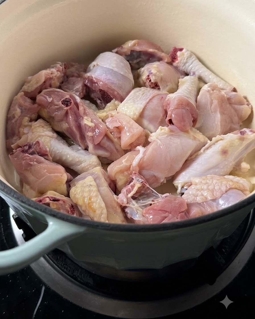 Vista ravvicinata di numerosi pezzi di pollo crudo nella pentola durante la rosolatura.