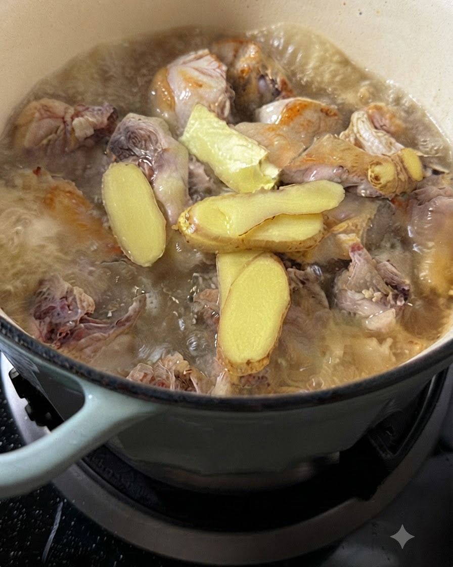 Acqua calda versata sul pollo e sulle spesse fette di zenzero in una pentola bollente.