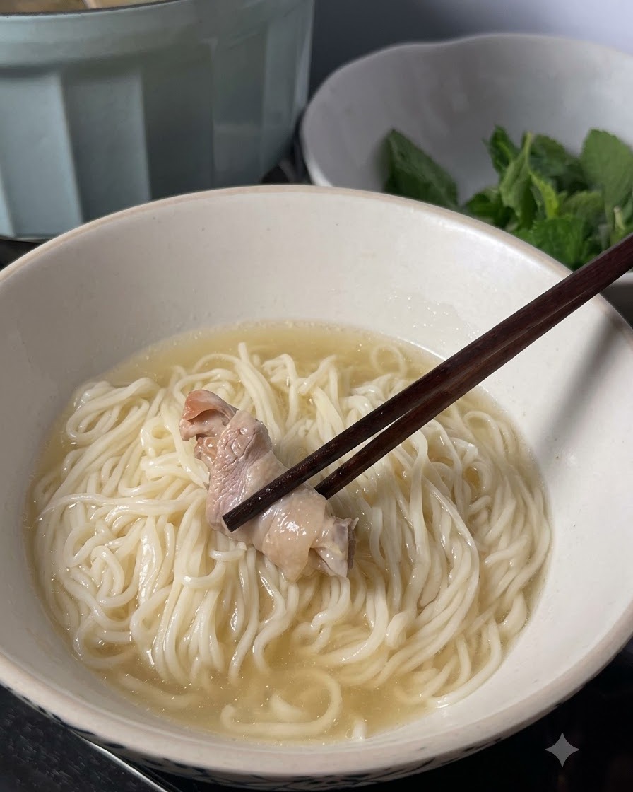 Le bacchette che posizionano un pezzo di pollo cotto sui noodles coperti di brodo in una ciotola.