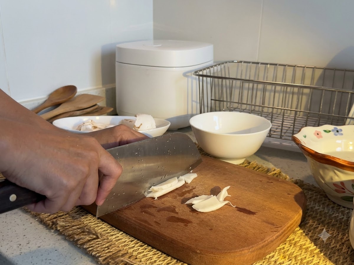 Polpa di cocco bianca affettata con una mannaia su un tagliere di legno.