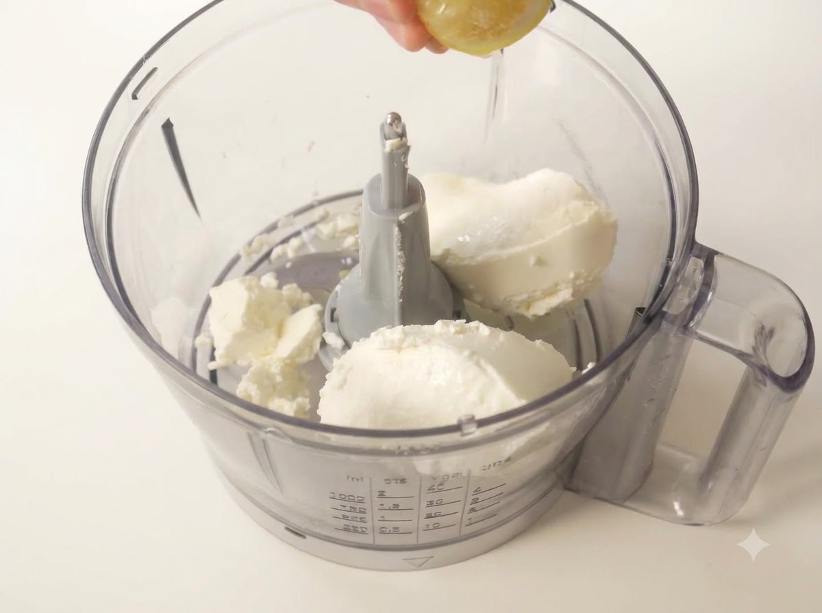Una metà di limone fresco spremuta a mano per farne uscire il succo nella ciotola del robot da cucina.