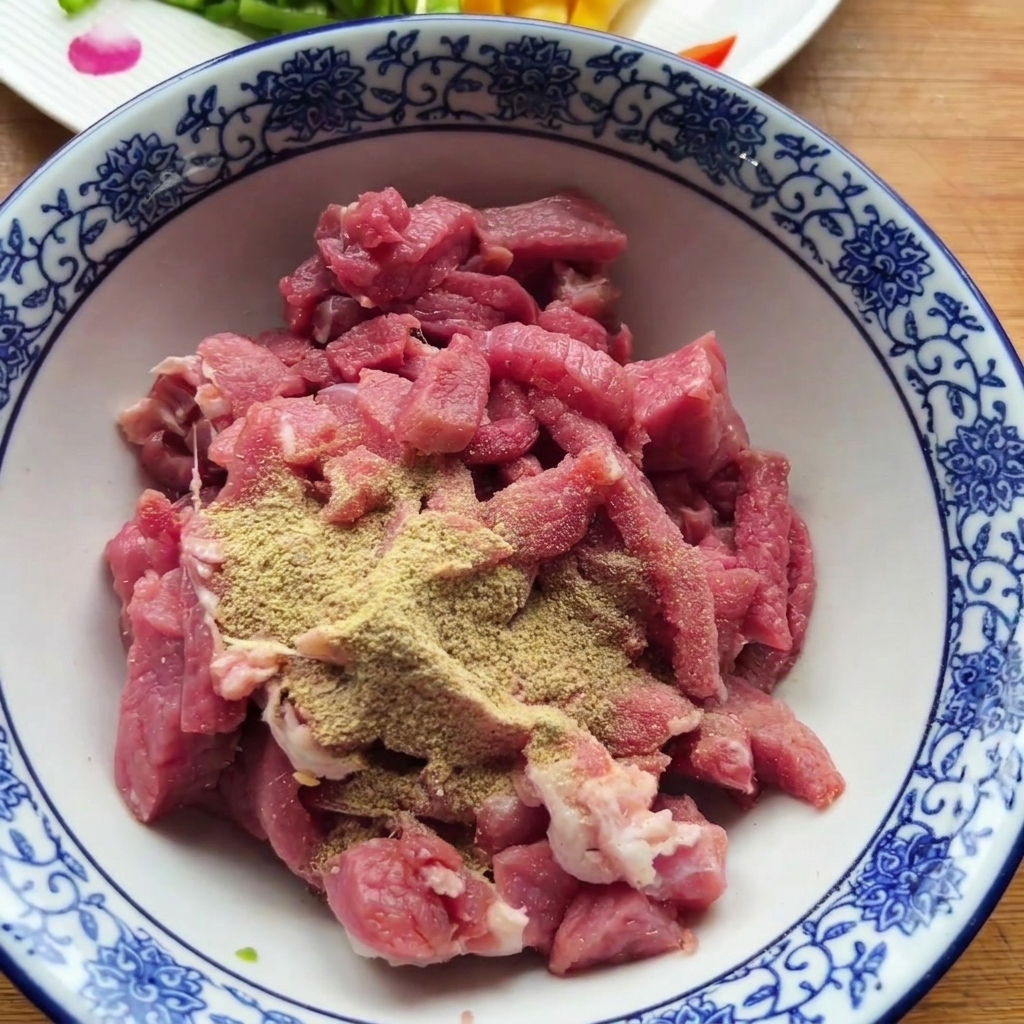 Pezzi di manzo crudo in una ciotola decorata guarniti con spezie in polvere secche.